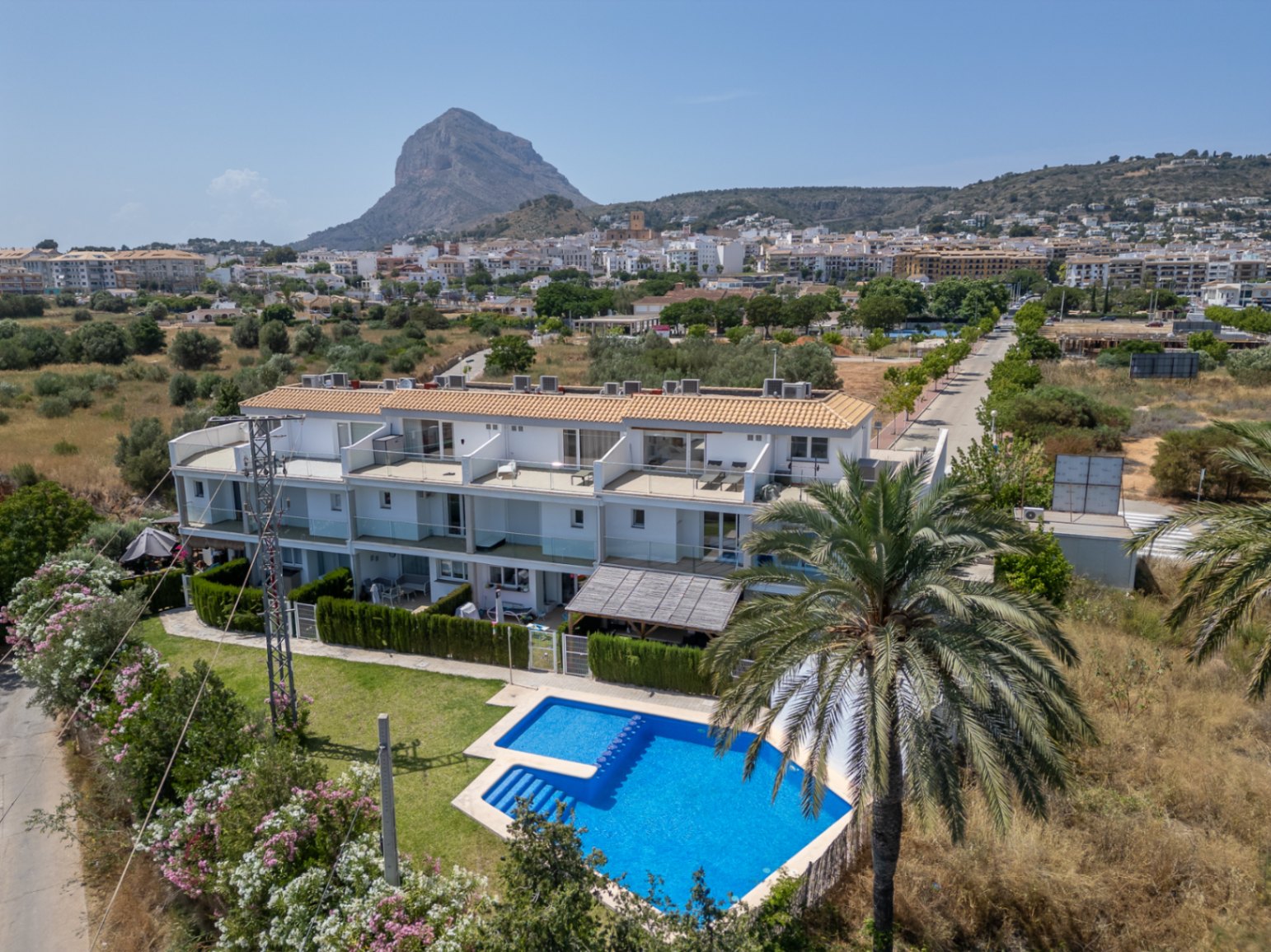 Luchtfoto van het moderne wooncomplex met gemeenschappelijk zwembad, privétuinen en uitzicht op de Montgó en het oude centrum van Jávea.