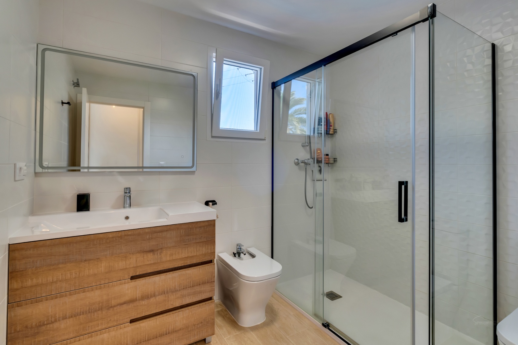 Moderne badkamer met houten wastafelmeubel, bidet en een ruime inloopdouche met zwart omlijste glazen deuren en getextureerde wandtegels.