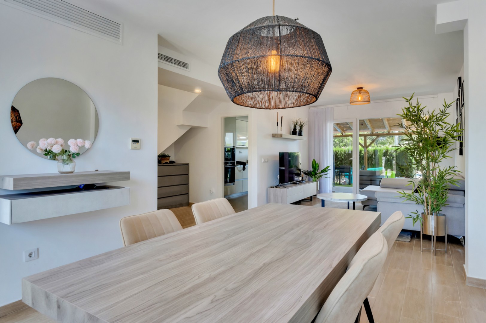 Open woon- en eetkamer met een grote houten eettafel, stijlvolle hanglamp en directe toegang tot het privéterras via de glazen schuifdeuren.