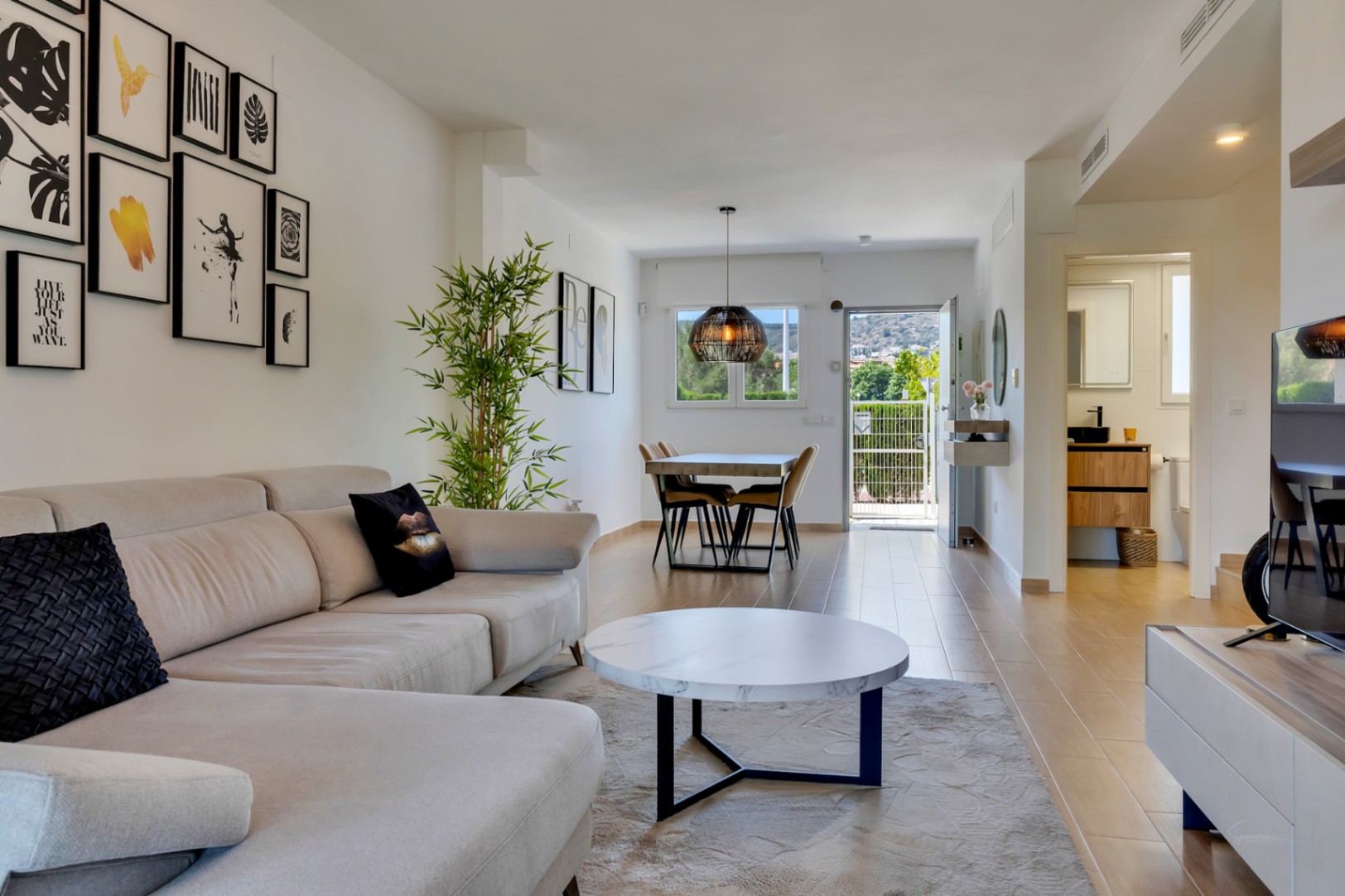 Open woon- en eetkamer voorzien van een houtlook tegelvloer, modern meubilair en een directe verbinding met de buitenruimte via de achterdeur.