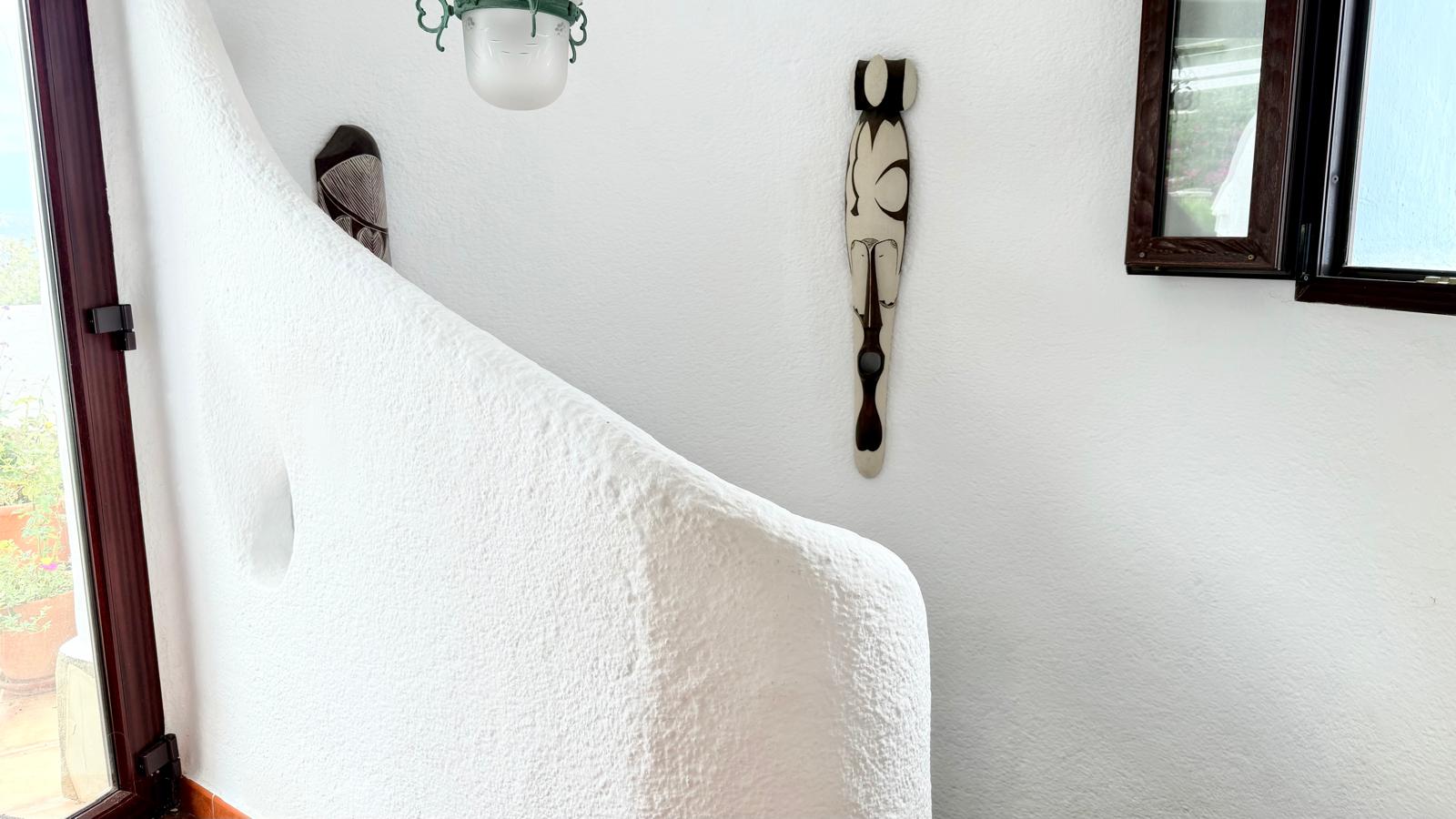 Detail van de gebogen binnentrap met wit gestuukte muren en organische vormen, kenmerkend voor de authentieke Ibiza-stijl van de woning.