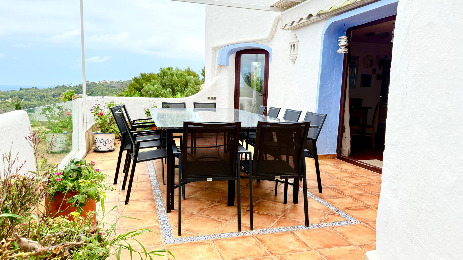 Hoofdterras met eethoek buiten, granieten tafel en terracotta vloer. De ruimte biedt panoramisch uitzicht op zee en kenmerkende Ibizaanse architectuur.