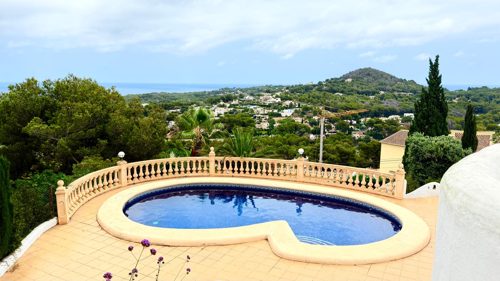 Niervormig privézwembad omgeven door een betegeld terras en klassieke balustrade, met panoramisch uitzicht op de Middellandse Zee en de kust van Jávea.
