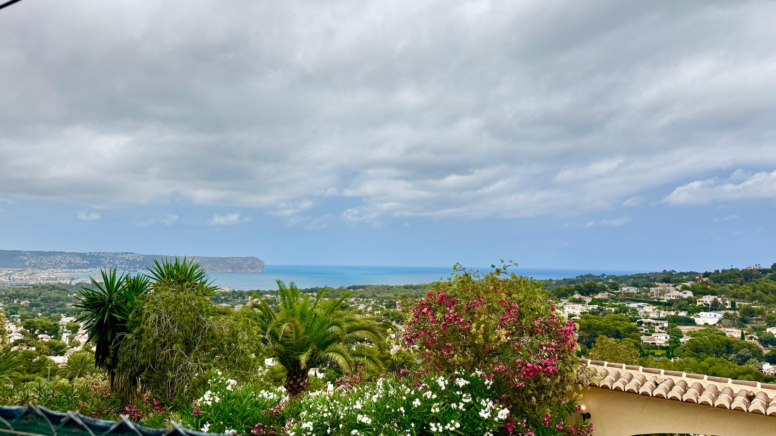 Panoramisch uitzicht op de Middellandse Zee en Cabo de San Antonio, omgeven door volgroeide mediterrane tuinen en weelderige flora.
