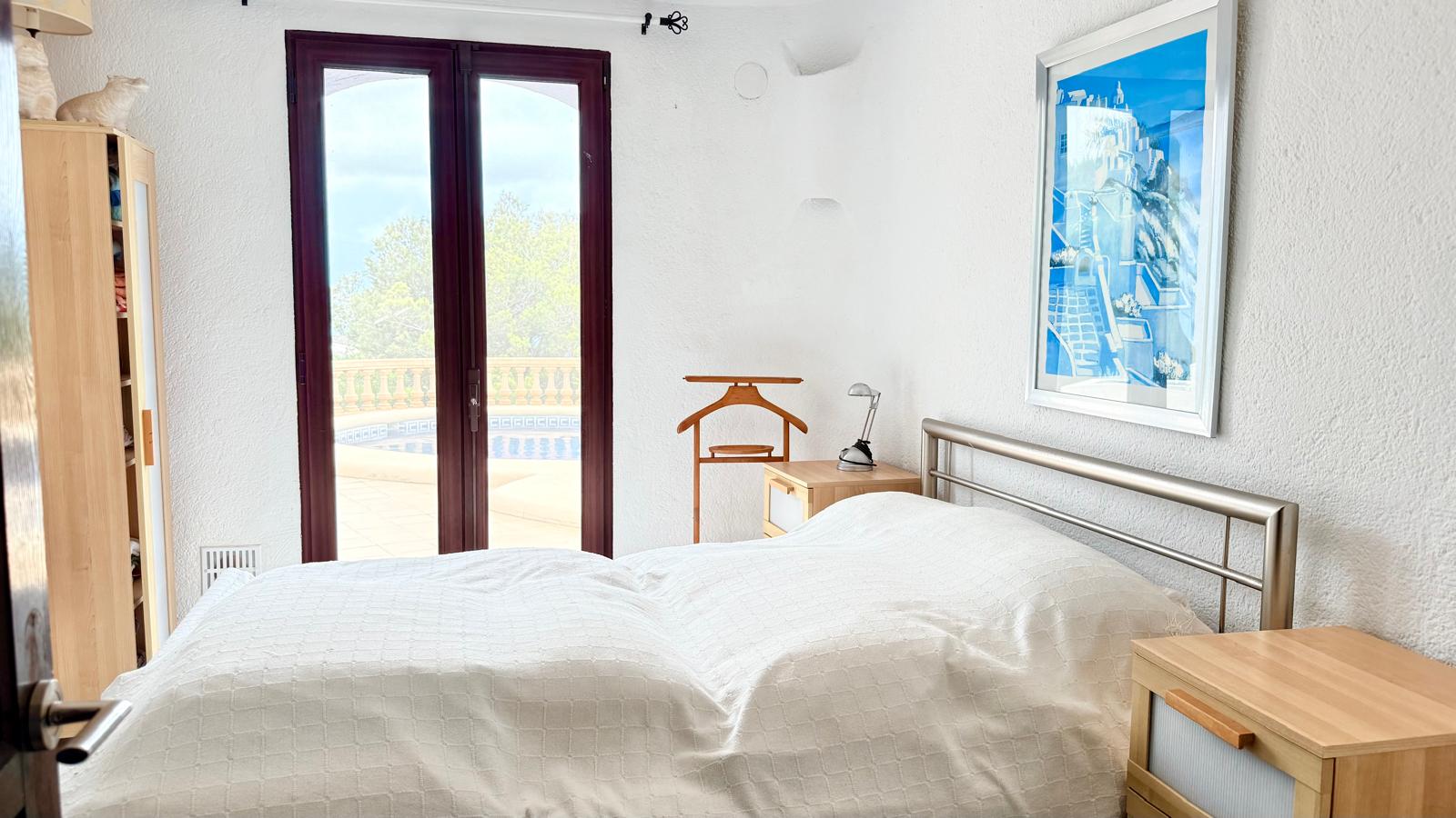 Slaapkamer met directe toegang tot het zwembad, witte muren in mediterrane stijl en functionele lichthouten meubels.