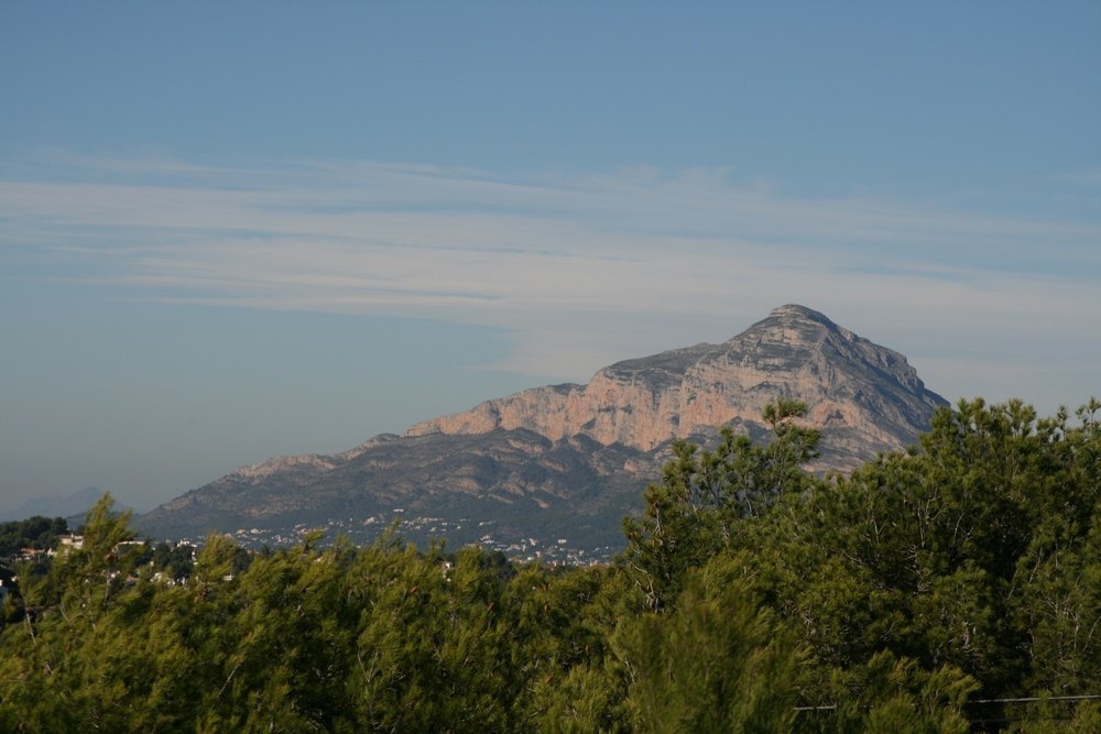 Panoramisch uitzicht op het Montgó-gebergte vanaf het perceel, met rotsachtige kliffen boven een voorgrond van mediterrane pijnbomen.