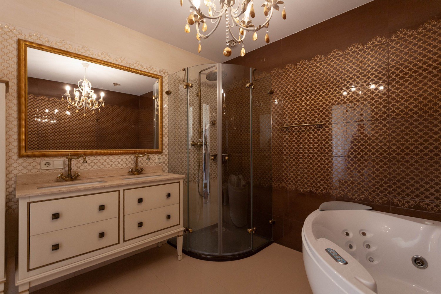 Badkamerdetail met dubbele wastafel, hoekdouche en jacuzzi. Elegante kroonluchterverlichting.