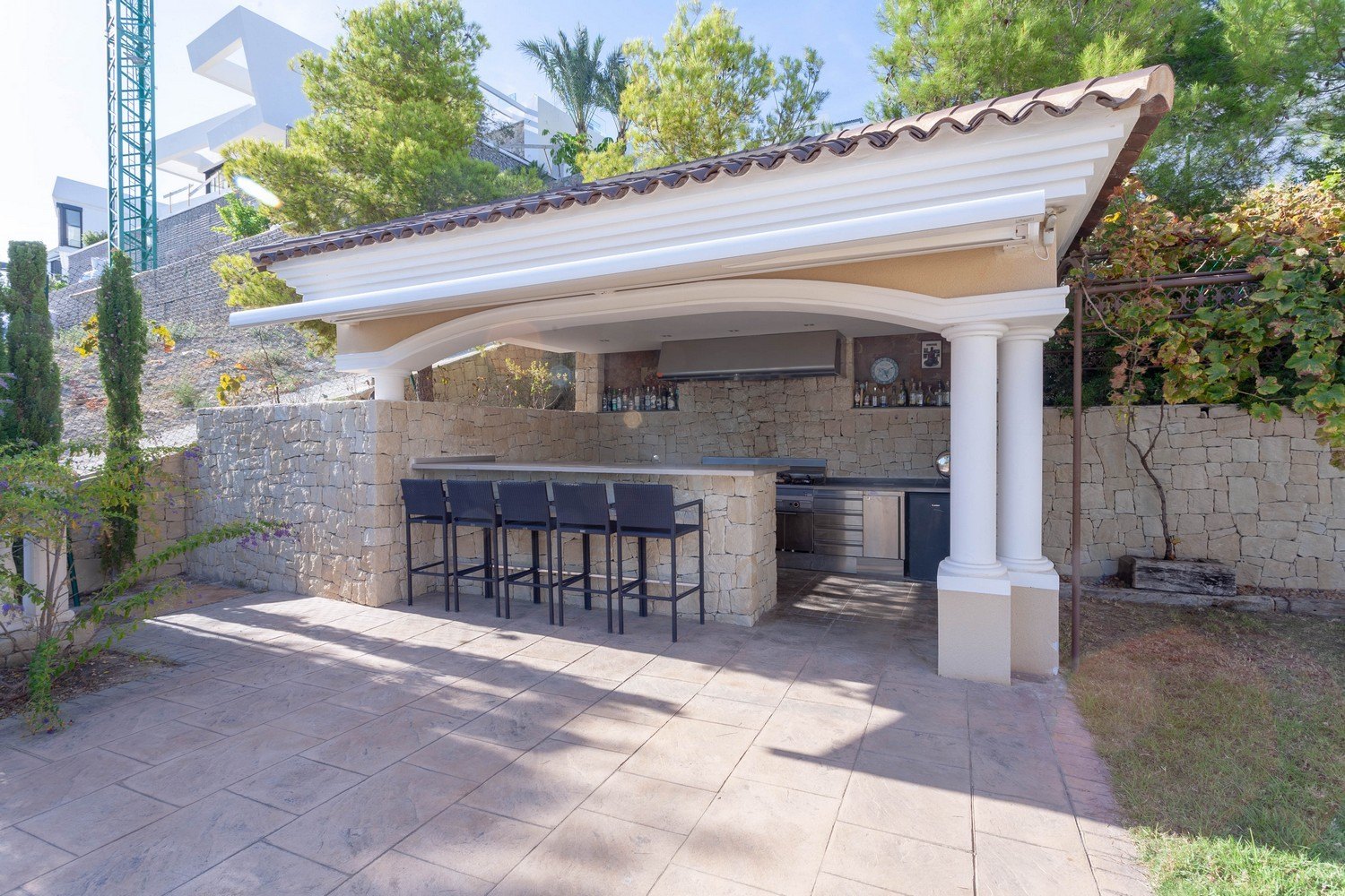 Buitenbarbecue met bar en krukken in villa in Benissa. Stenen bekleding en roestvrijstalen aanrecht.