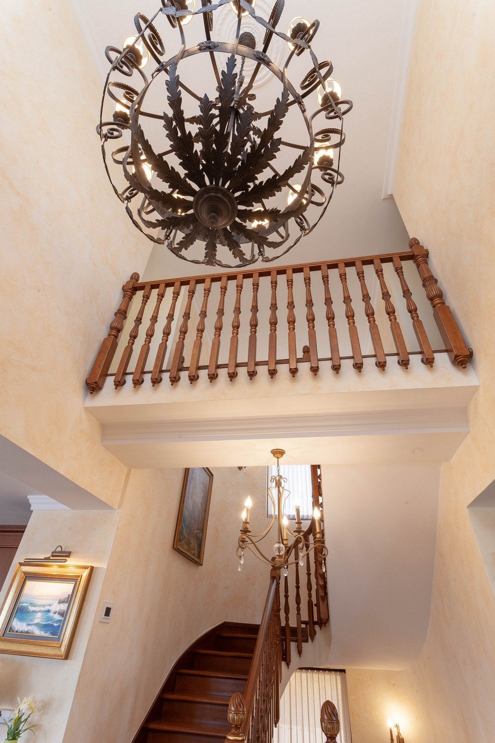 Detail van de houten trap met leuning en decoratieve kroonluchter.