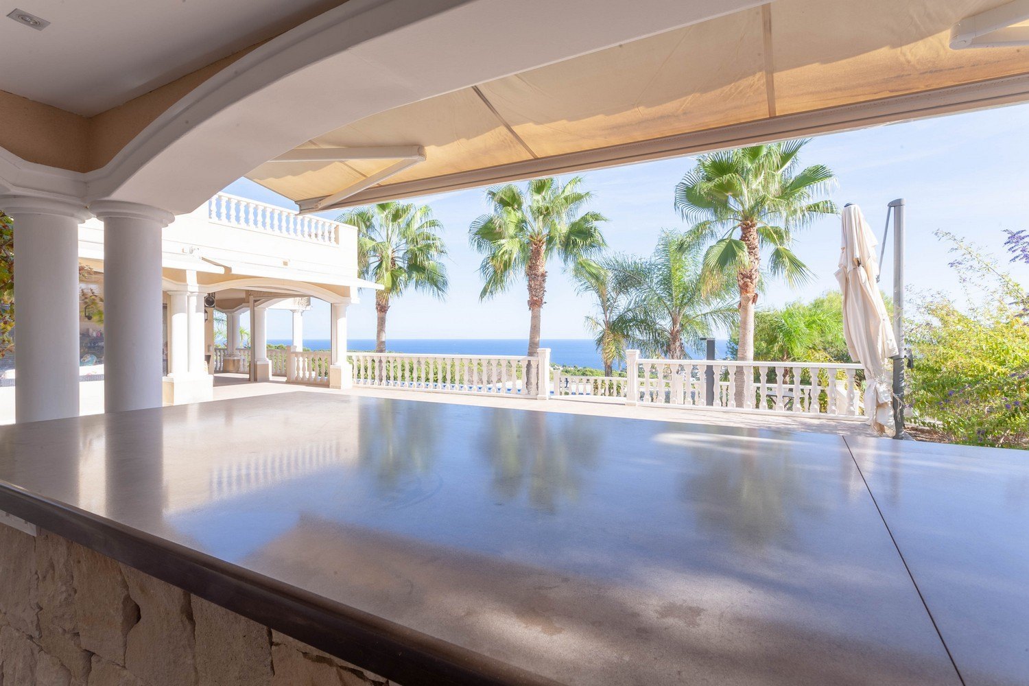 Overdekt terras met stenen bar, uitzicht op zee en palmbomen in Raco de Galeno, Benissa.