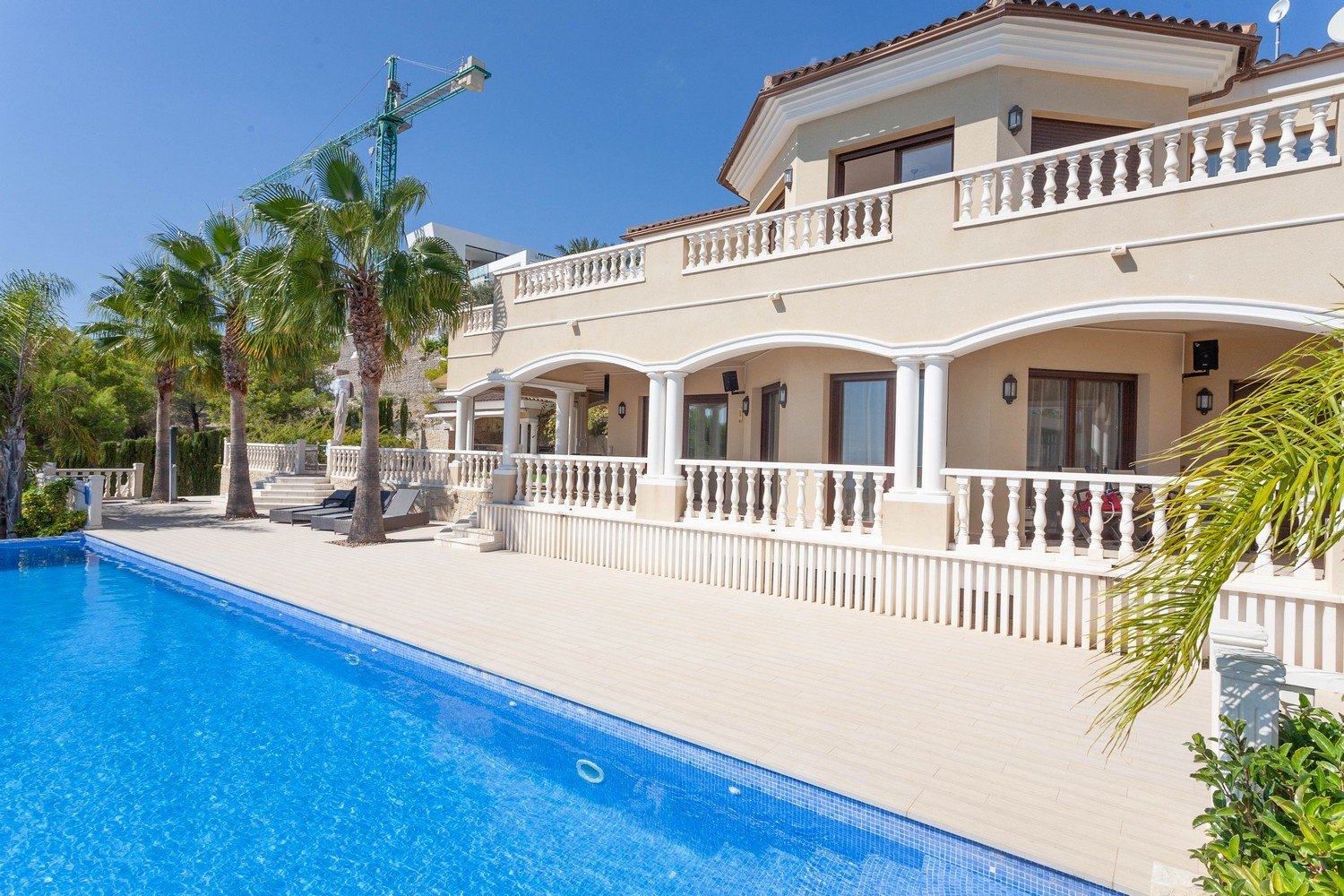 Uitzicht op het zwembad en de gevel van de mediterrane villa met witte balustrade.