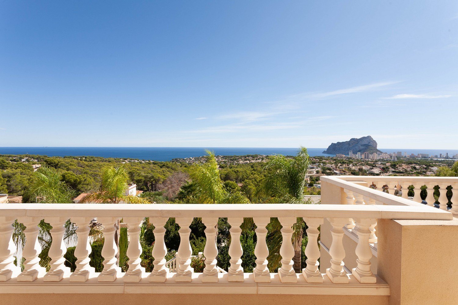 Uitzicht vanaf het terras met stenen balustrade richting de zee en Peñón de Ifach.
