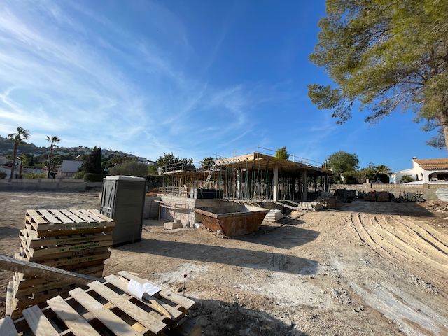 Villa in aanbouw in Moraira: betonstructuur met metalen steunen onder een blauwe hemel.