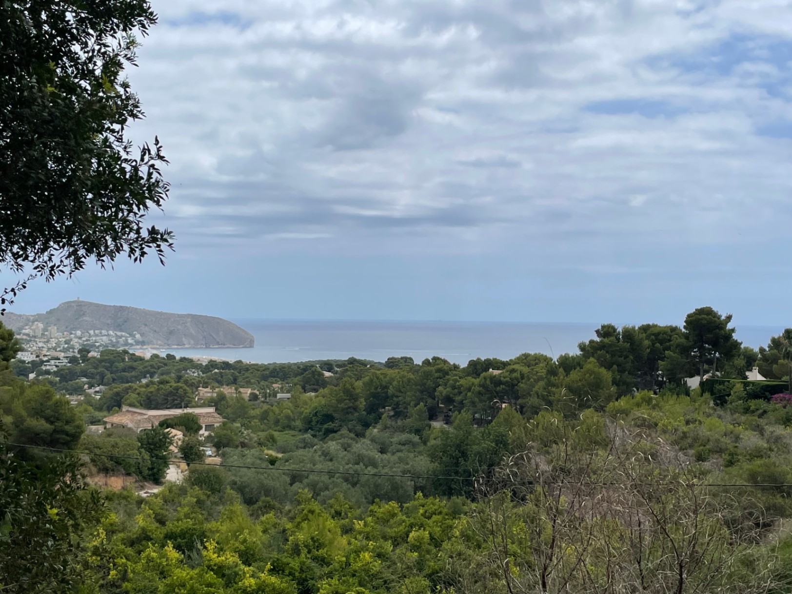 Verhoogd panoramisch uitzicht vanaf het perceel over de Middellandse Zee en Cap d'Or, omgeven door pijnbomen en weelderige mediterrane vegetatie.