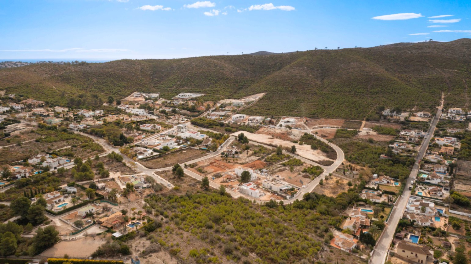 Panoramisch luchtfoto van de woonwijk Lomas Del Rey in Jávea, met villa's verspreid over de groene mediterrane heuvels.