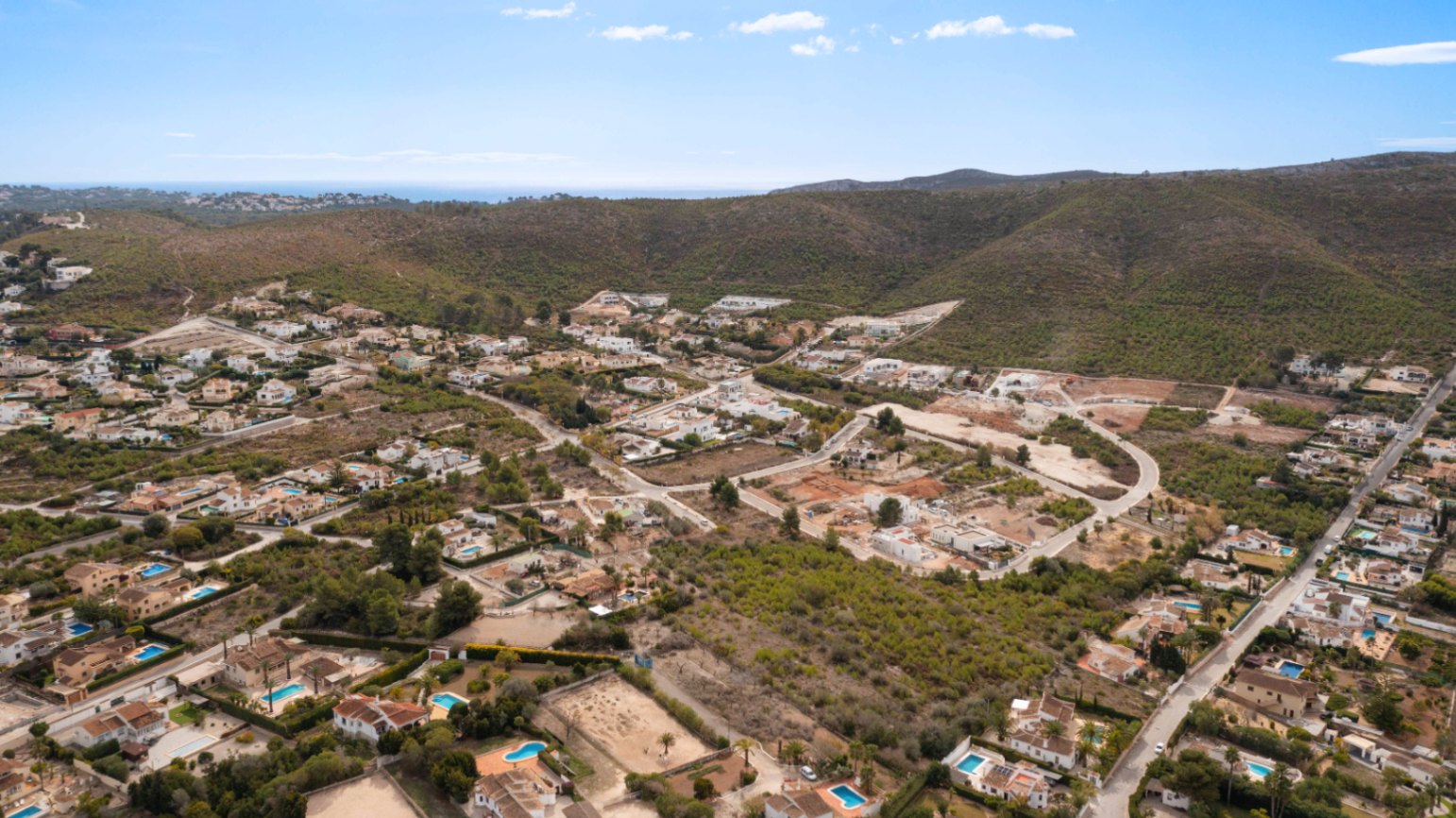 Panoramisch luchtfoto van de woonwijk Lomas Del Rey in Jávea, met vrijstaande villa's omgeven door groene heuvels en een weids uitzicht op de Middellandse Zee.