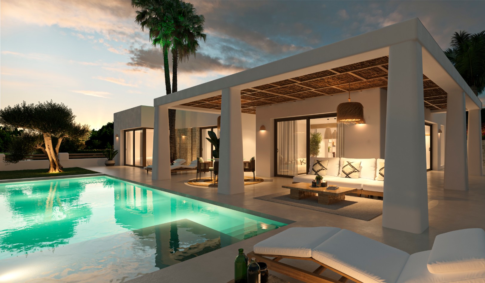 Exterieur van een villa in Ibiza-stijl met verlicht zwembad, overdekt terras met natuurlijk rieten plafond en loungehoek bij zonsondergang.