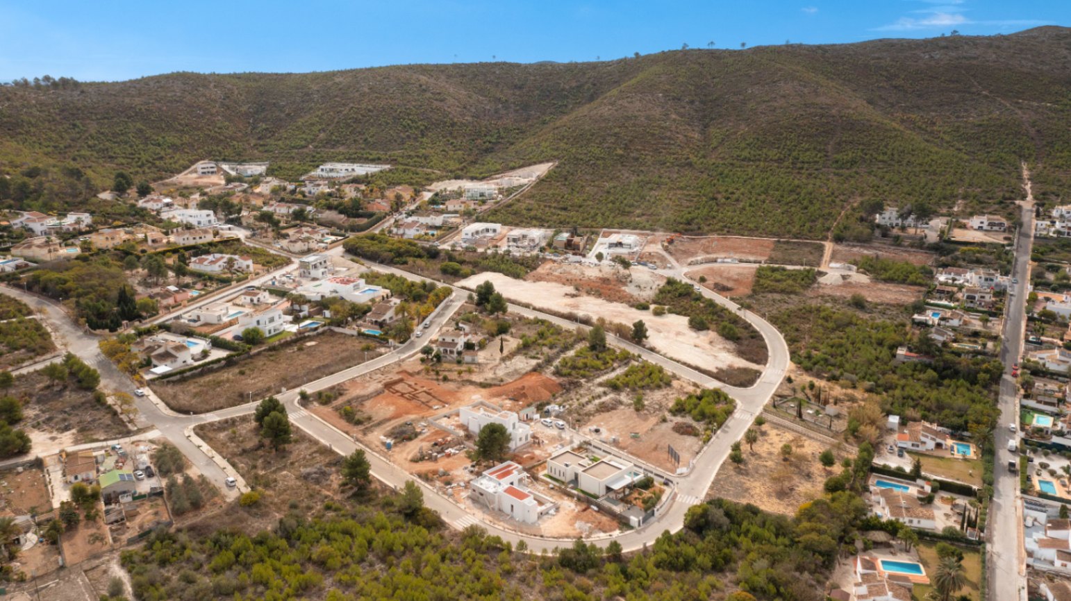 Luchtfoto van de ontwikkeling Lomas Del Rey in Jávea, met bouwpercelen en villa's in aanbouw aan de voet van de beboste heuvels.