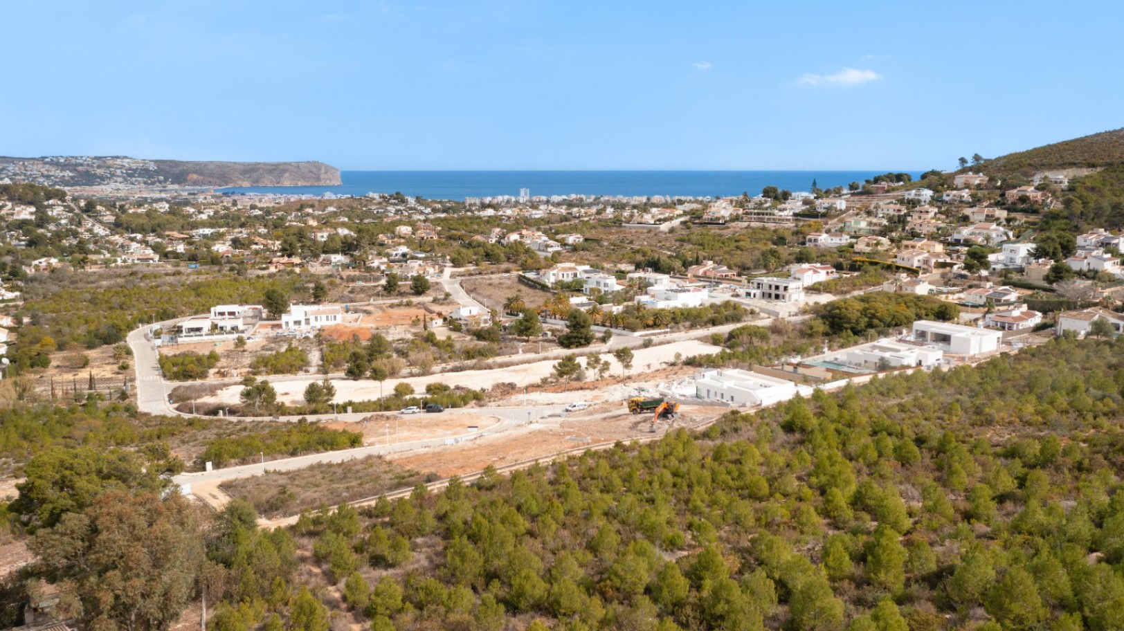 Panoramisch luchtfoto van het perceel in Lomas Del Rey, Jávea, met uitzicht op het omliggende dennenbos en de weidse Middellandse Zee en kustlijn.