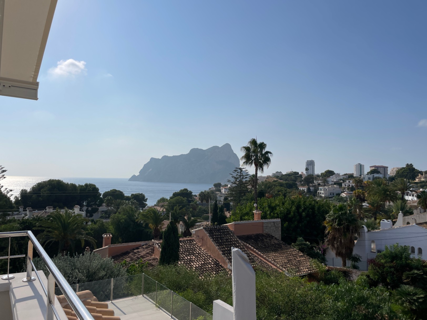 Panoramisch uitzicht vanaf een terras met roestvrijstalen en glazen balustrade op de Peñón de Ifach en de Middellandse Zeekust.