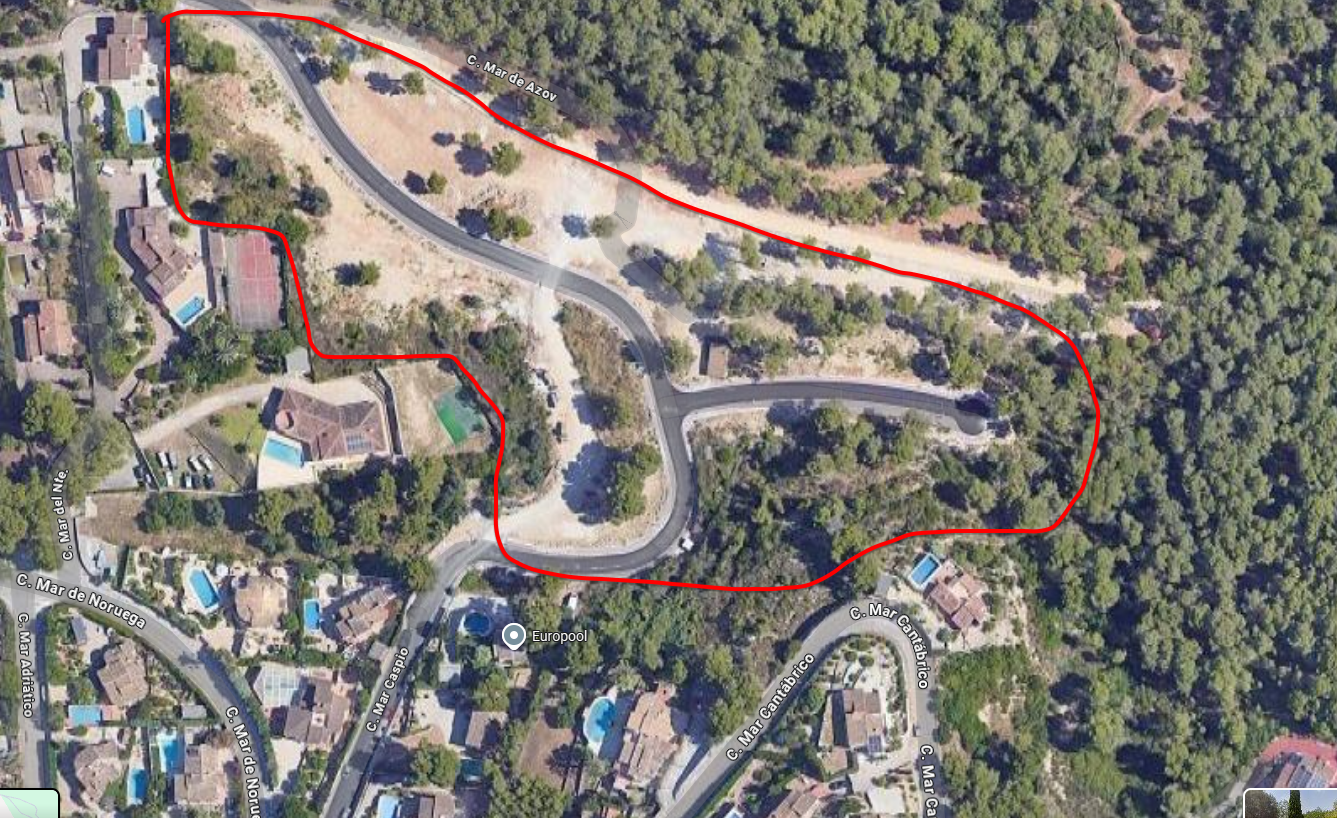 Luchtfoto van een rood omlijnd bouwperceel met geasfalteerde toegangswegen en mediterrane vegetatie, gelegen nabij villa's met zwembaden.