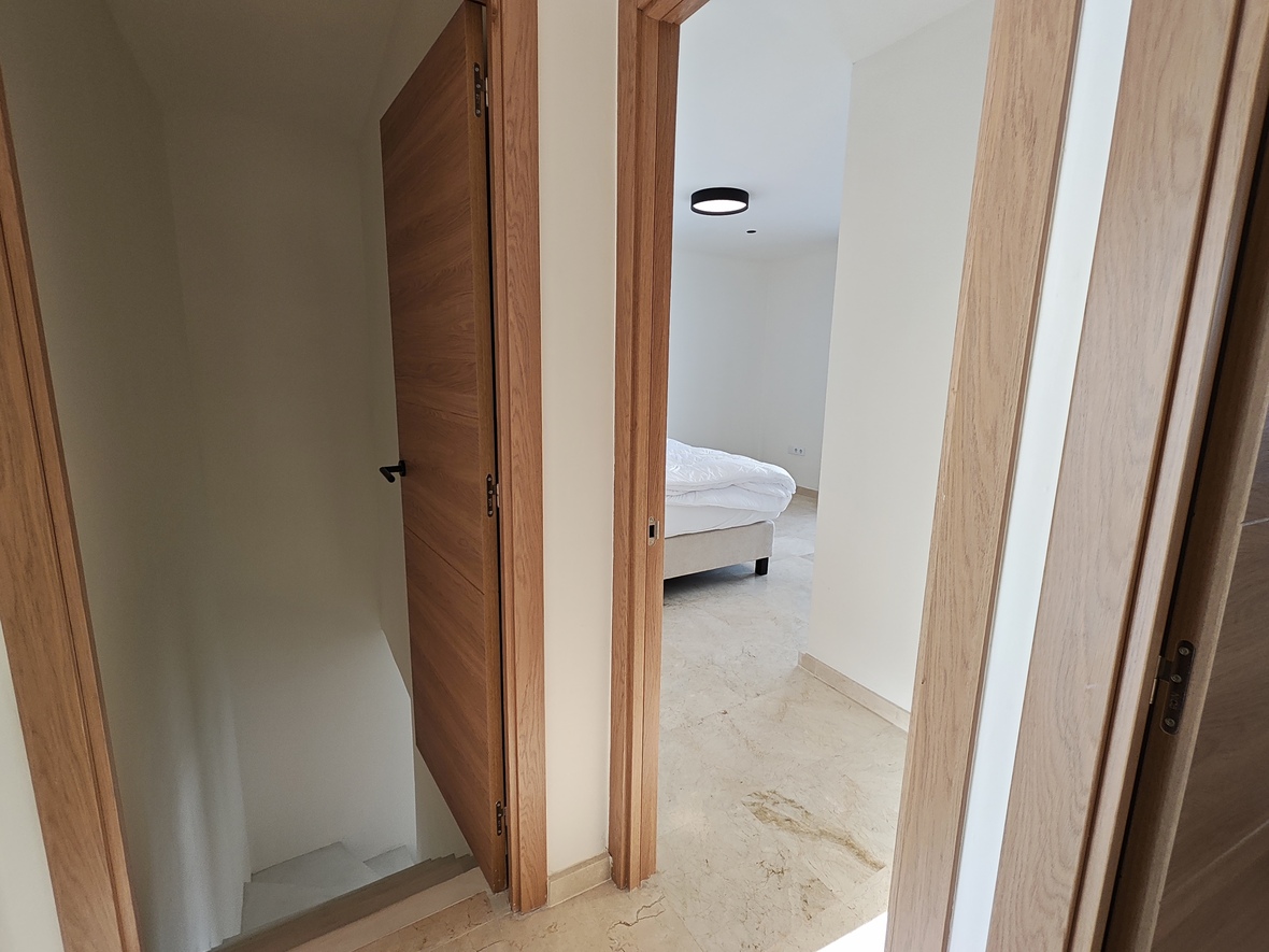 Overloop met eikenhouten deuren en natuurstenen vloer, die toegang biedt tot een slaapkamer en de trap naar de benedenverdieping.