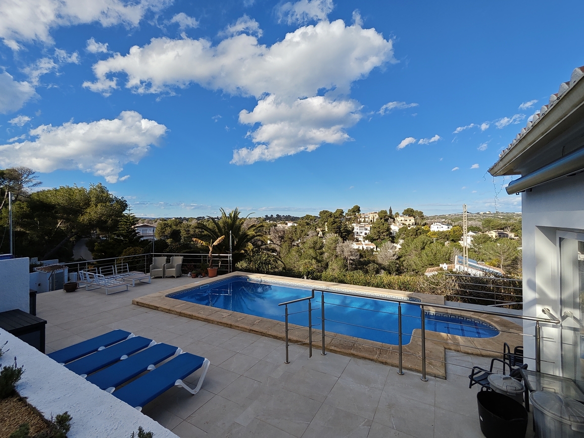 Verhoogd terras met een rechthoekig zwembad, roestvrijstalen balustrades en panoramisch uitzicht over het mediterrane landschap en de vallei.