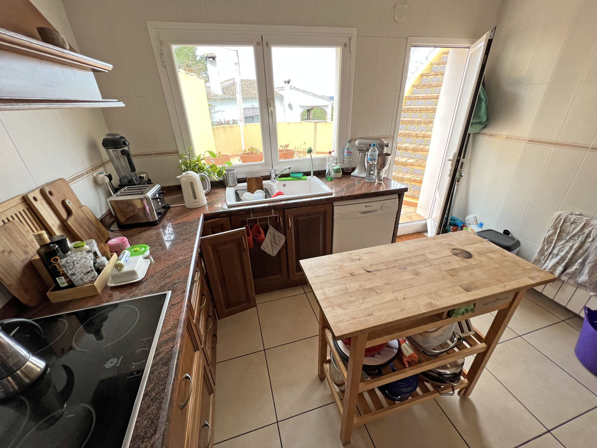 Aparte keuken met granieten werkbladen, houten kasten en een verplaatsbaar kookeiland. De deur biedt toegang tot een buitentrap met traditionele tegels.