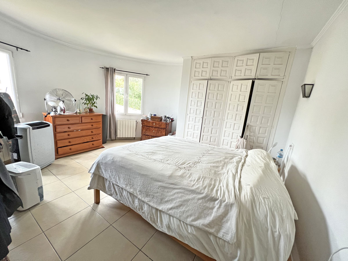 Lichtrijke slaapkamer met ruime ingebouwde kasten in traditionele stijl, tegelvloer en houten meubilair met natuurlijke lichtinval.