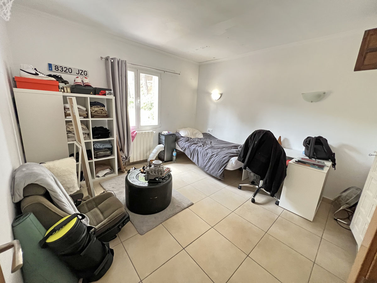 Slaapkamer in de onafhankelijke studio met keramische tegelvloer, witte muren en natuurlijk licht. De ruimte is geschikt voor een bureau en opbergkasten.