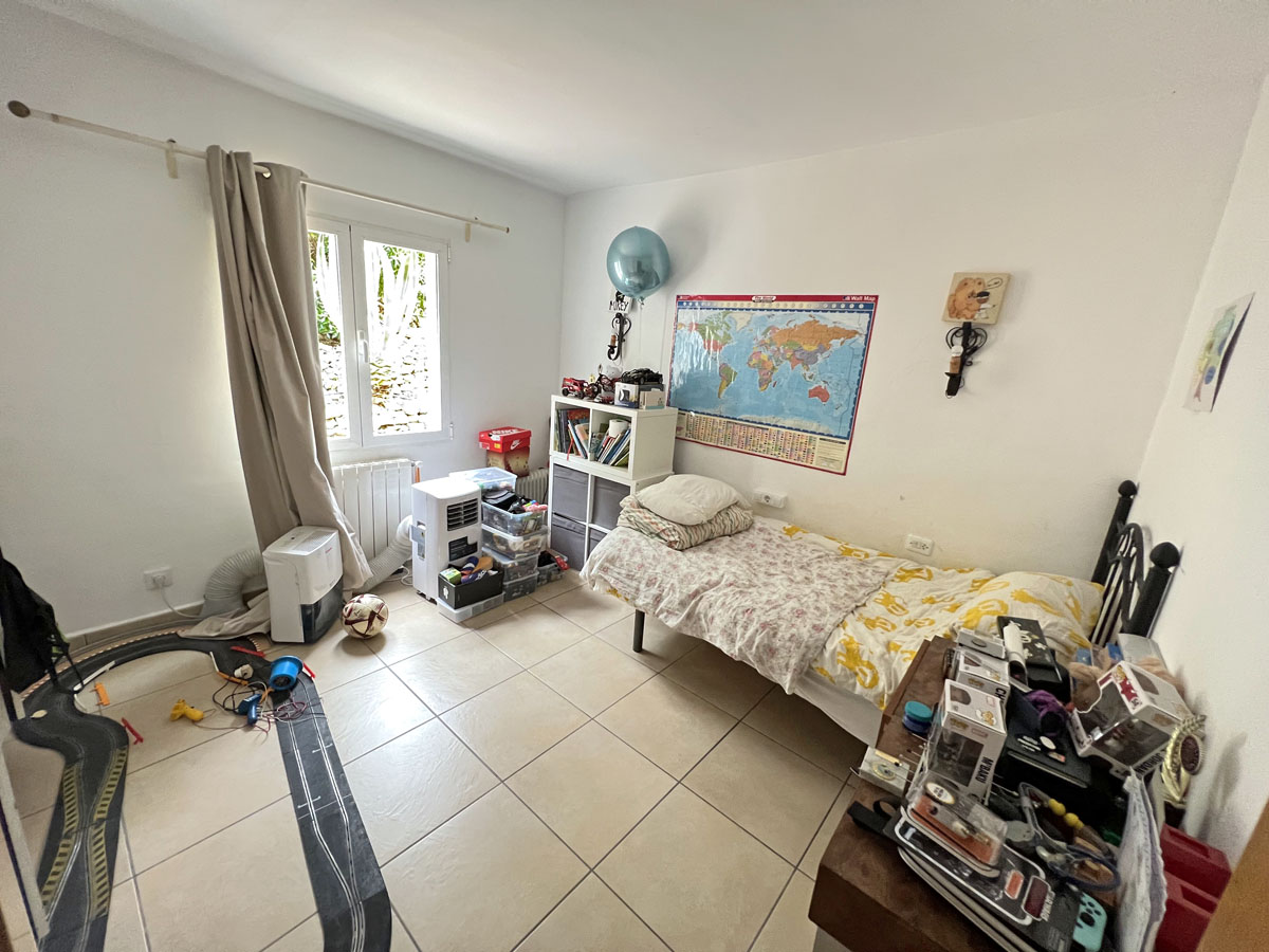 Slaapkamer met tegelvloer, radiator en een raam voor natuurlijk licht. De ruimte is voorzien van witte muren en een functionele indeling.