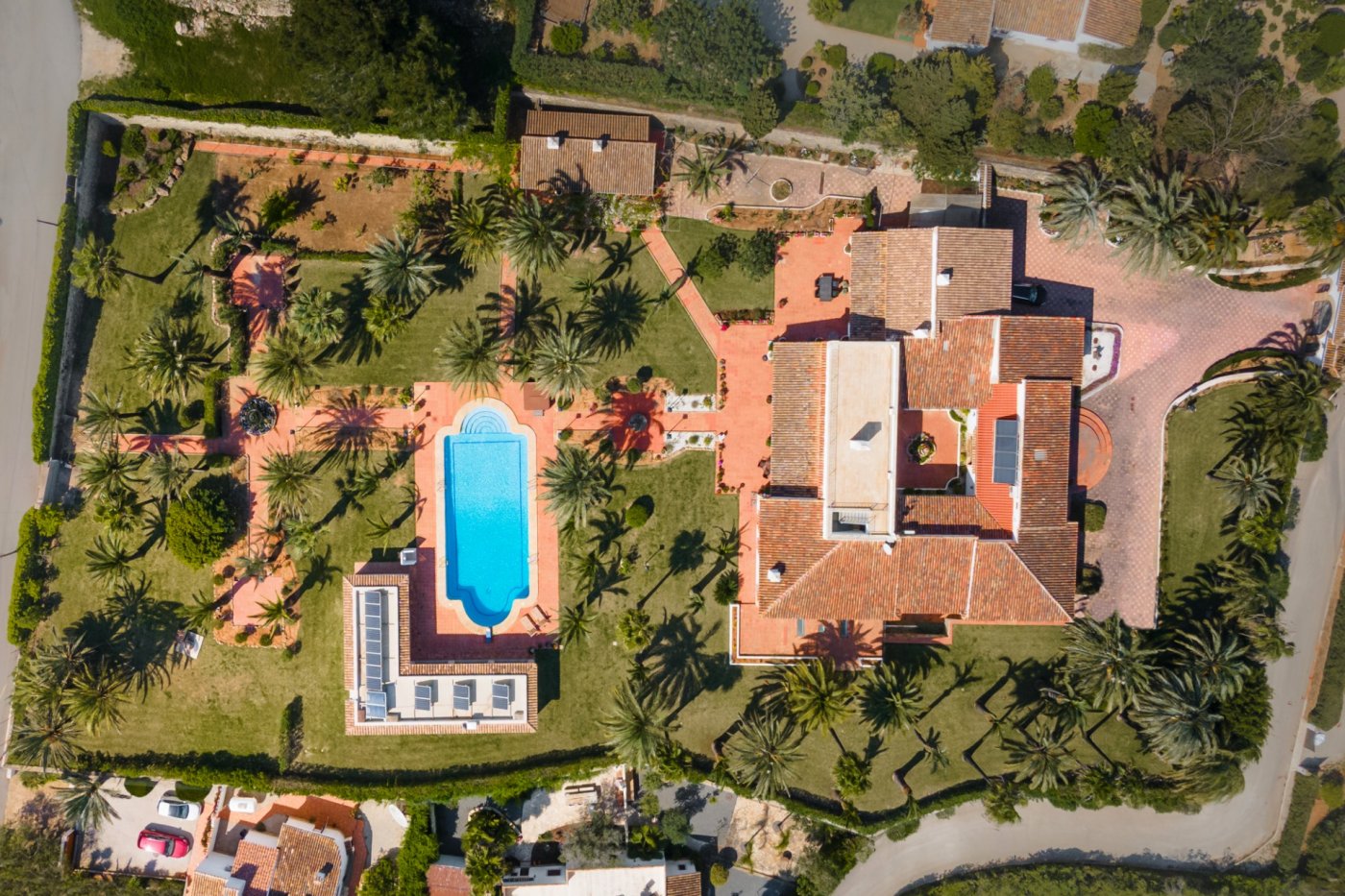 Luchtfoto van het perceel van 5.835 m2 met de villa met centrale patio, het zwembad van 16x7 m en de mediterrane tuin met talrijke palmbomen.
