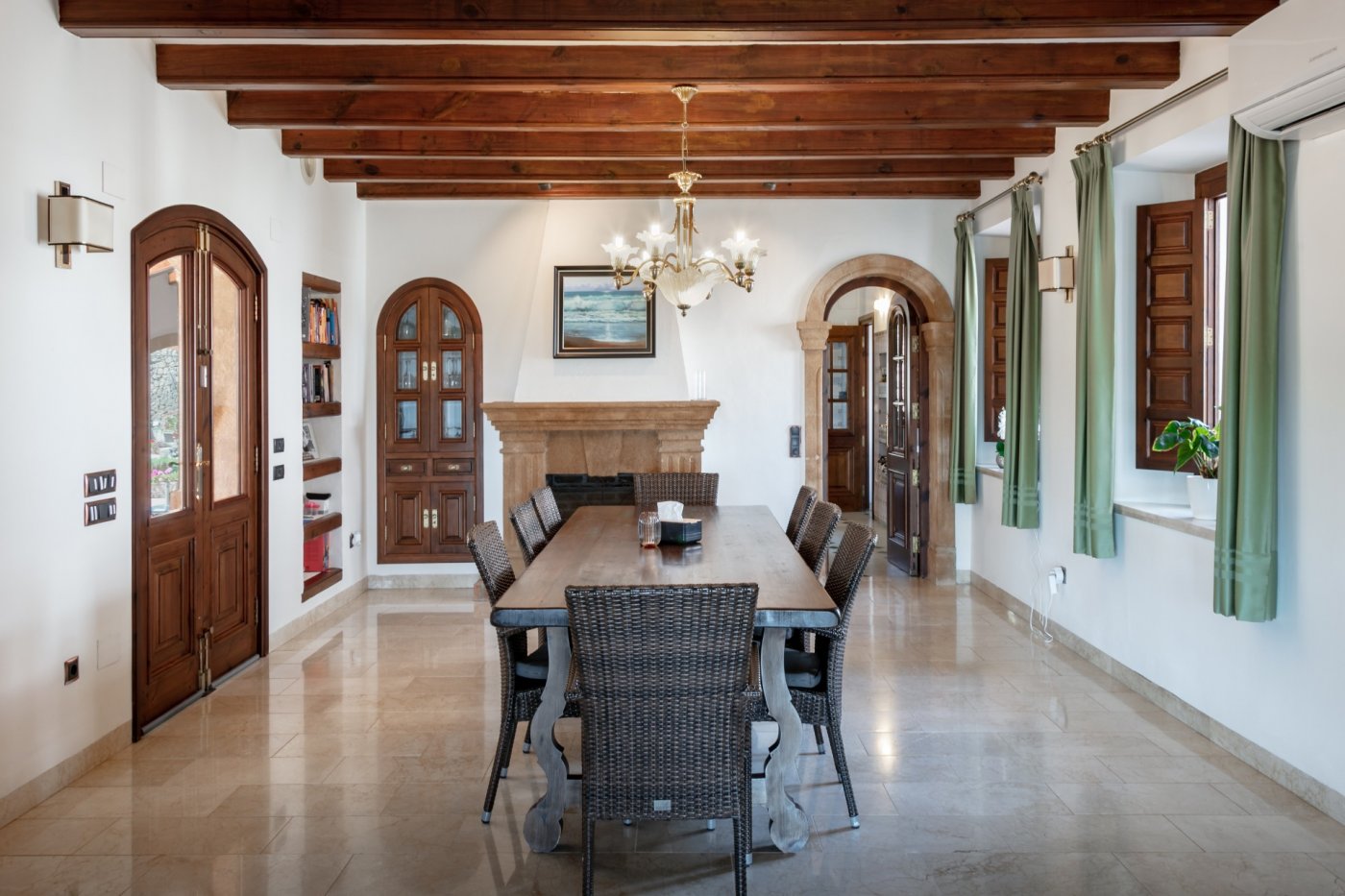 Traditionele eetkamer met houten balkenplafond, een Tosca stenen open haard en een robuuste houten tafel. Mediterrane bogen en marmeren vloeren sieren de ruimte.