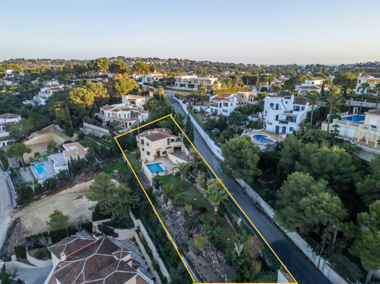 Luchtfoto van de villa met gemarkeerde perceelgrenzen, voorzien van een privézwembad en een terrasvormige mediterrane tuin op een verhoogde locatie.