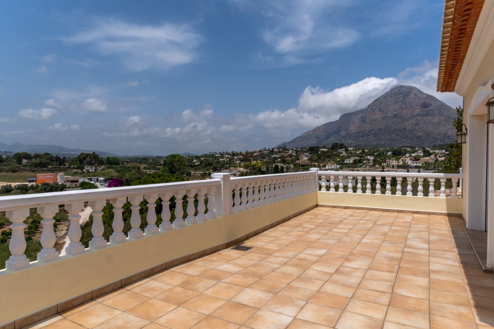 Bovenliggend terras met terracotta plavuizen en een witte balustrade, met weids panoramisch uitzicht op de Montgó-berg en de omliggende vallei.