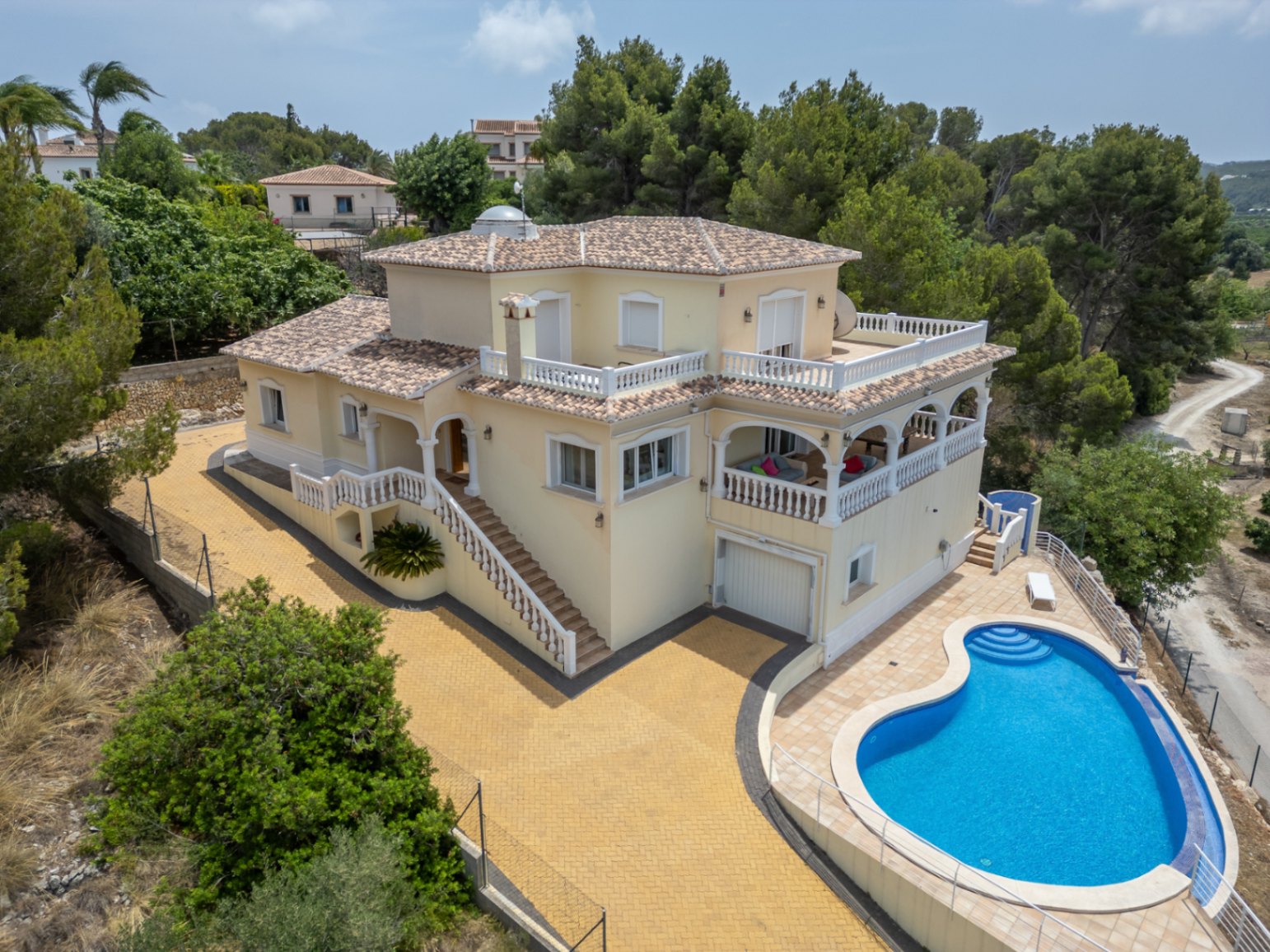 Luchtfoto van de mediterrane villa met niervormig zwembad, ruime terrassen met witte balustrades, een gewelfde naya en een glazen koepel op het dak.