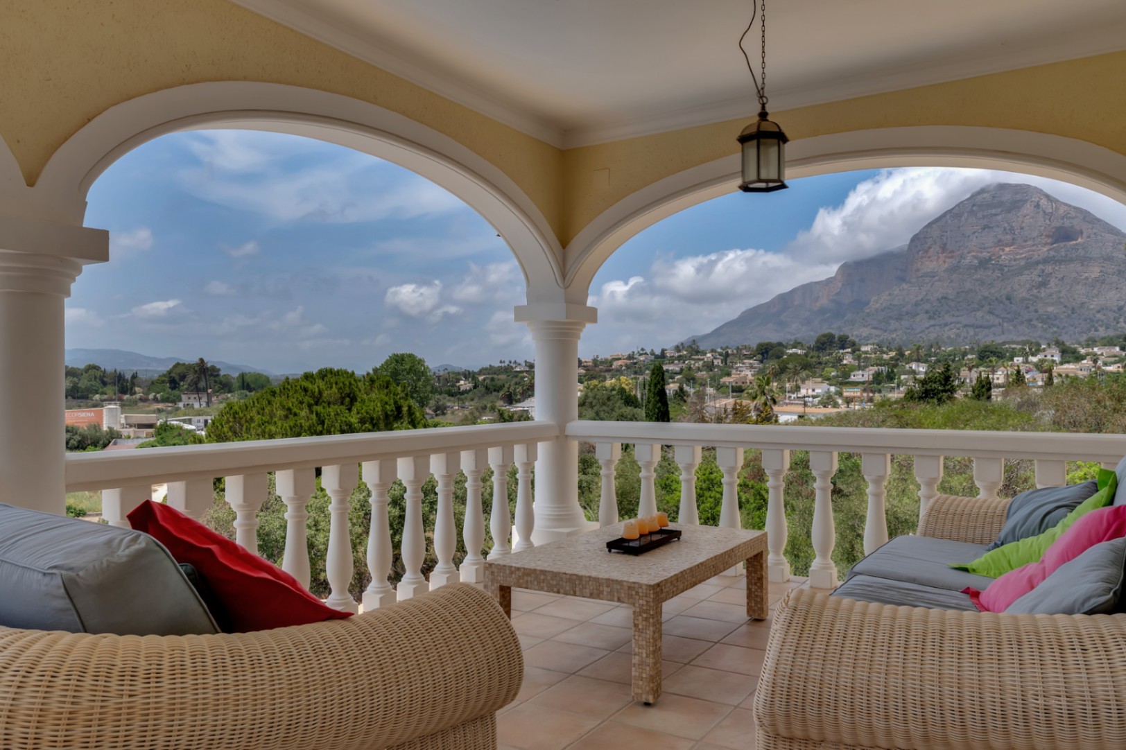 Overdekt terras met klassieke bogen, rieten meubilair en panoramisch uitzicht op de Montgó-berg en de omliggende vallei in Jávea.