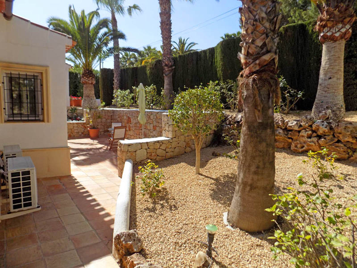 Mediterrane tuin met volwassen palmbomen, natuurstenen muren en terracotta tegels. Onderhoudsvriendelijke aanleg met grind en hoge hagen voor maximale privacy.