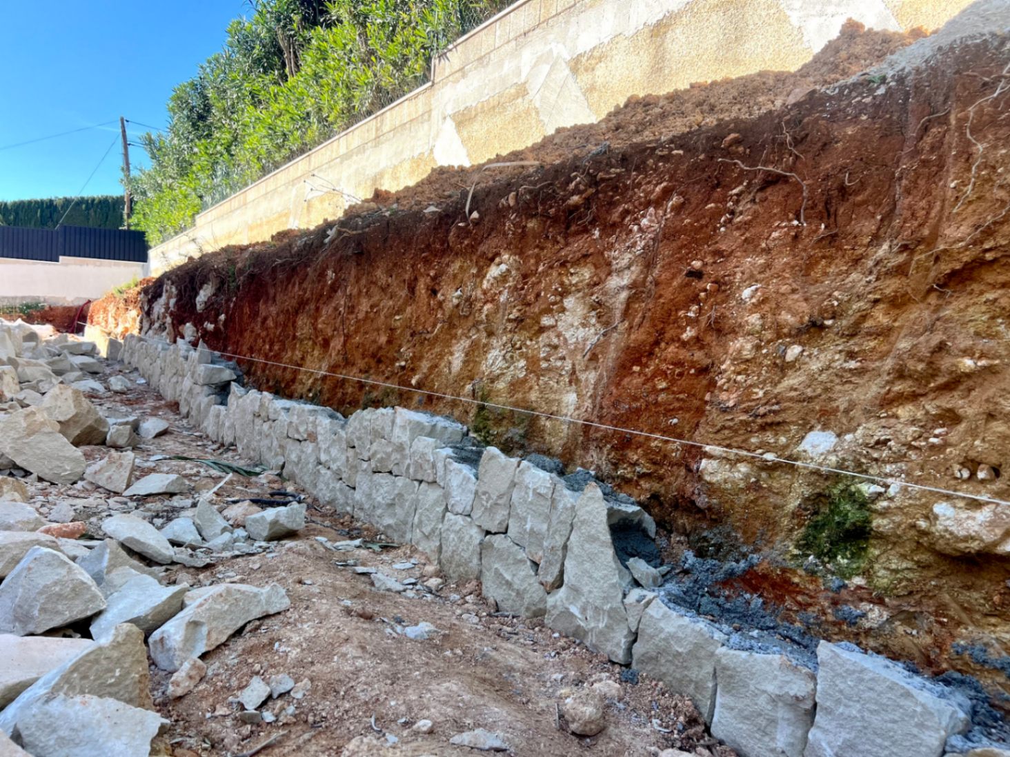 Eerste bouwfase van de villa met de constructie van een natuurstenen steunmuur tegen de uitgegraven aarde op het perceel.