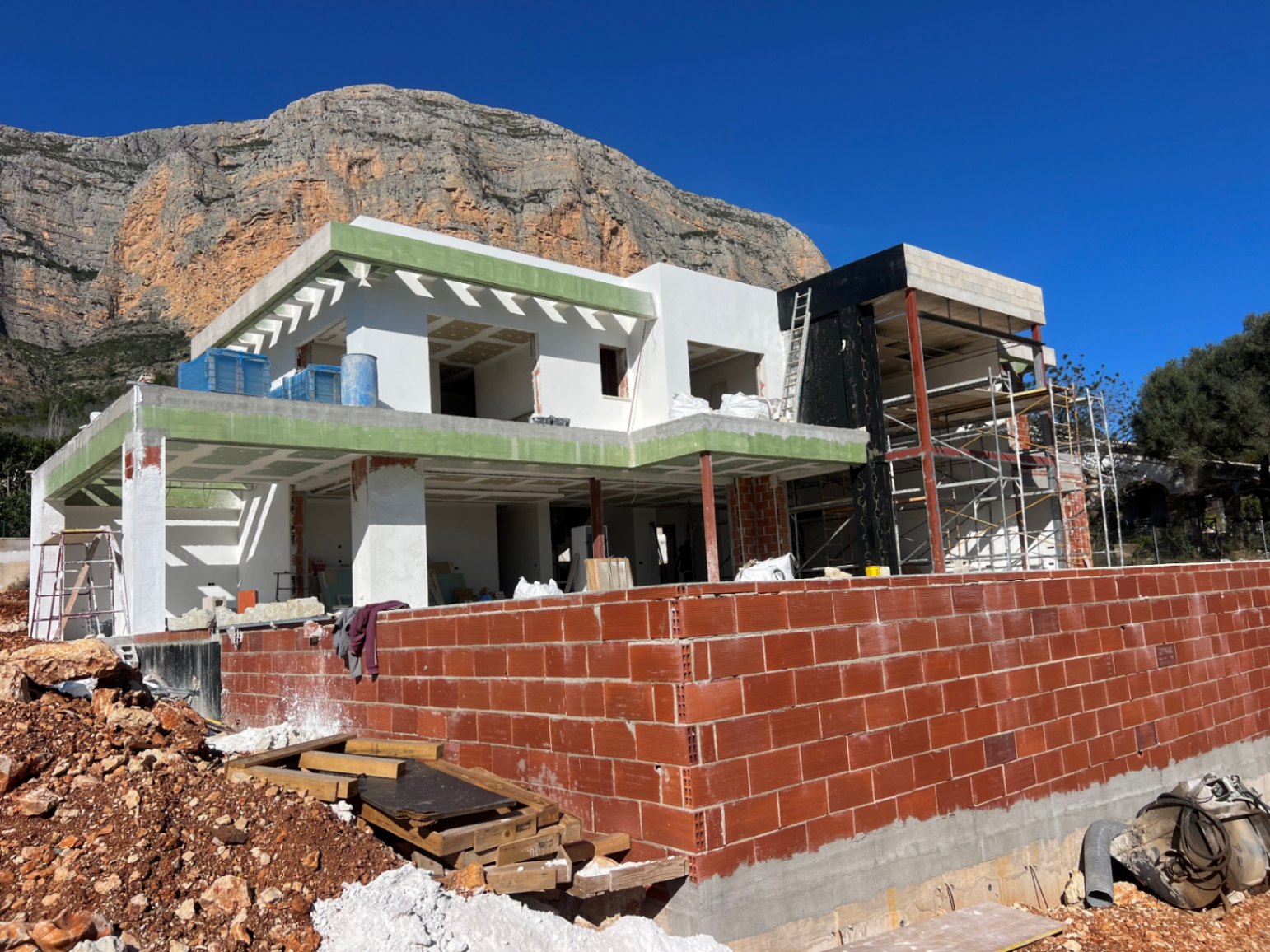 Exterieur van de villa in aanbouw met het Montgó-gebergte op de achtergrond, met de tweelaagse betonstructuur en ruime toekomstige terrassen.