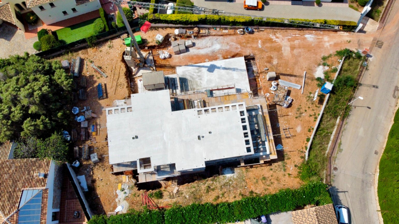 Luchtfoto van de voortgang van de bouw op het vlakke perceel, met de betonstructuur en bouwkraan op de locatie in El Garroferal.