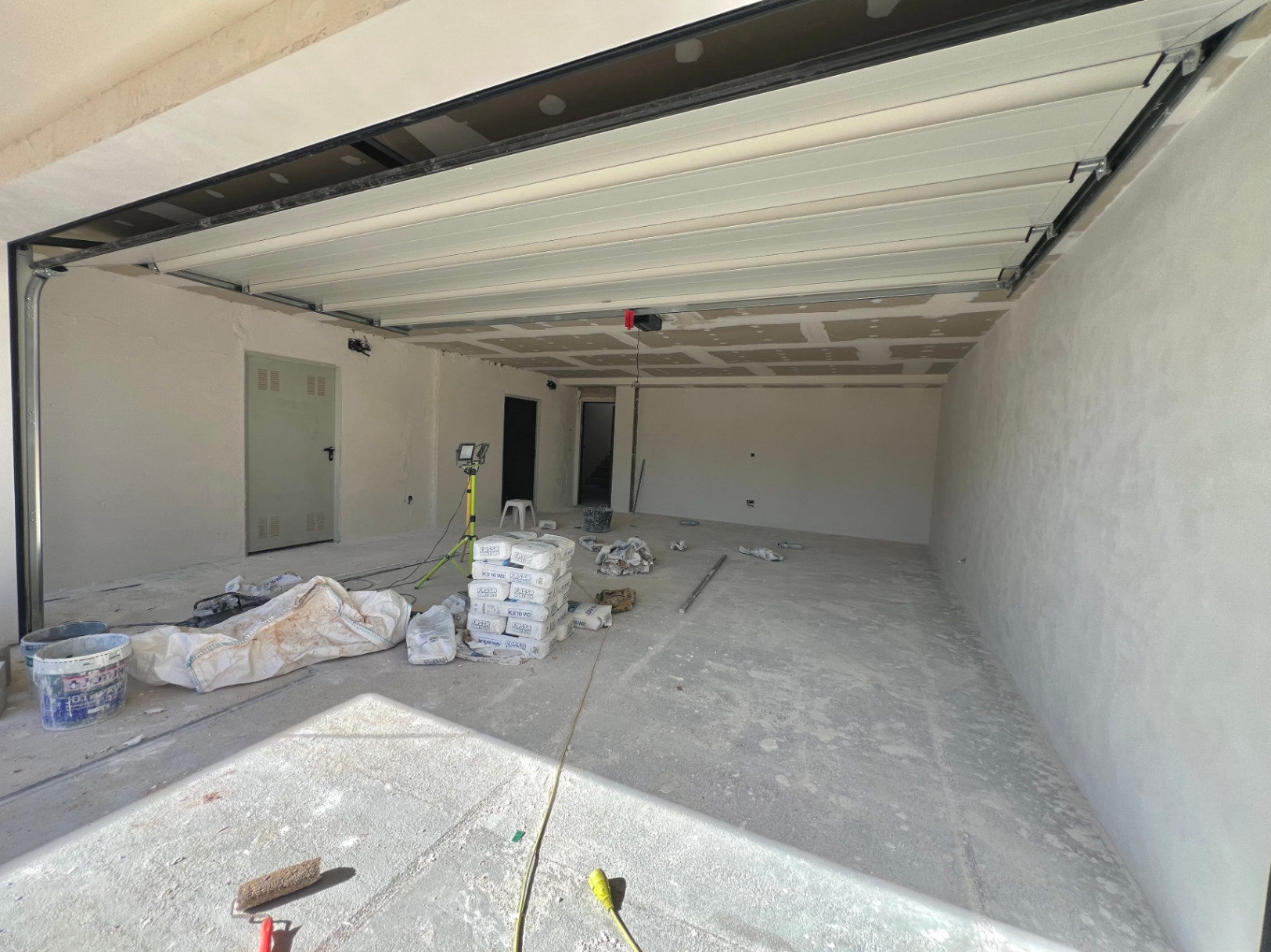 Ruime garage in aanbouw met automatische sectionaaldeur, betonnen vloer en directe toegang tot het interieur van de villa in Jávea.