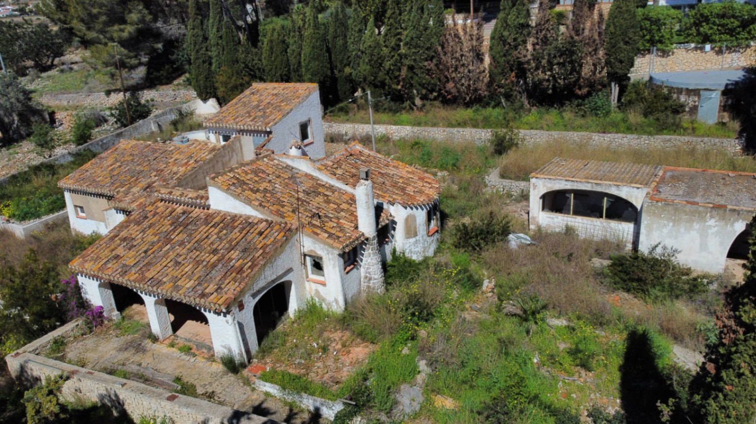 Luchtfoto van de villa met authentieke pannendaken, een naya met bogen en een stenen schoorsteen, gelegen op een groot perceel met volgroeide begroeiing.