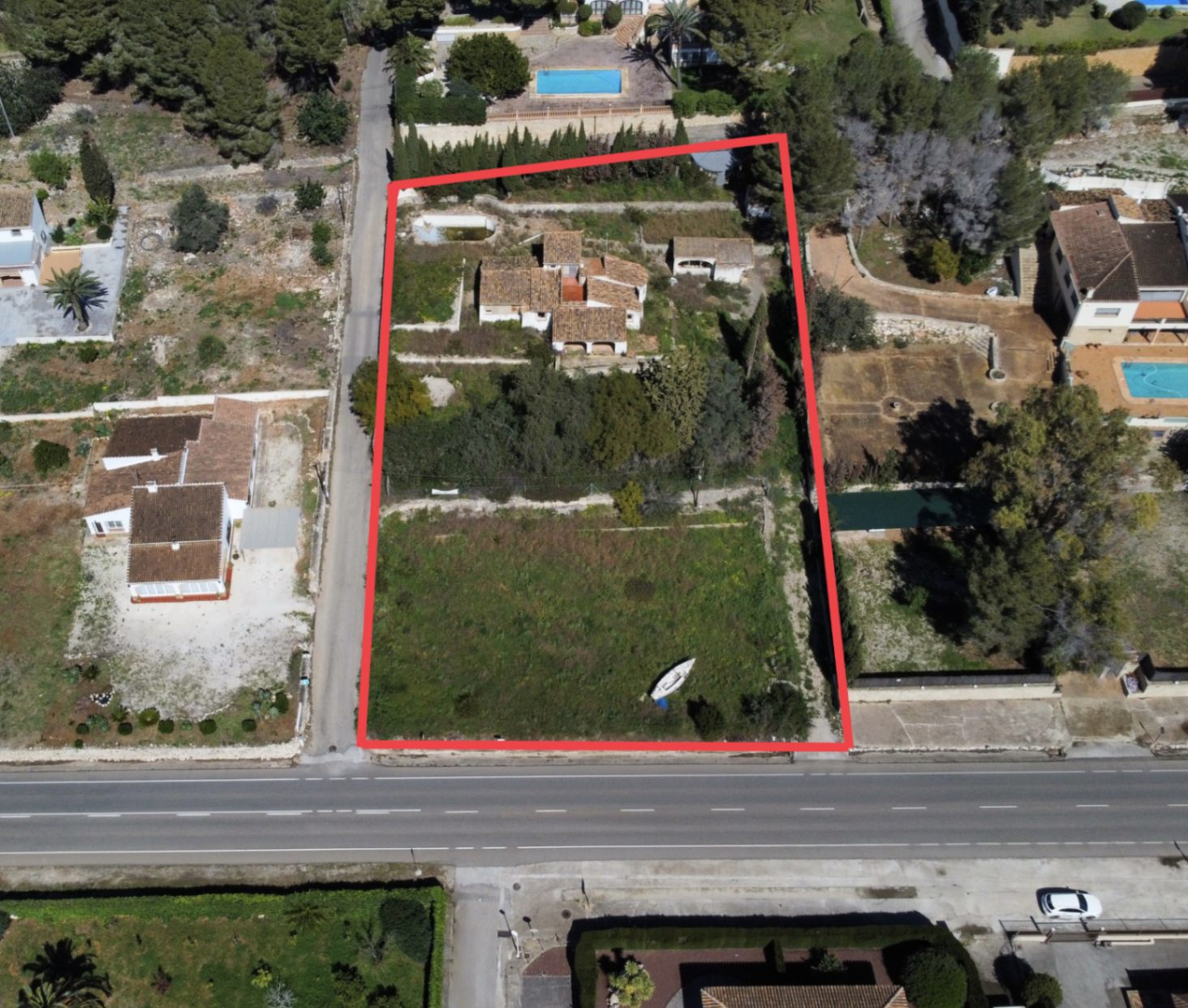 Luchtfoto van het perceel van 2.895 m2 in Montgó, Jávea, met de hoofdwoning, bijgebouwen en een groot vlak tuingedeelte met directe toegang tot de weg, rood omlijnd.