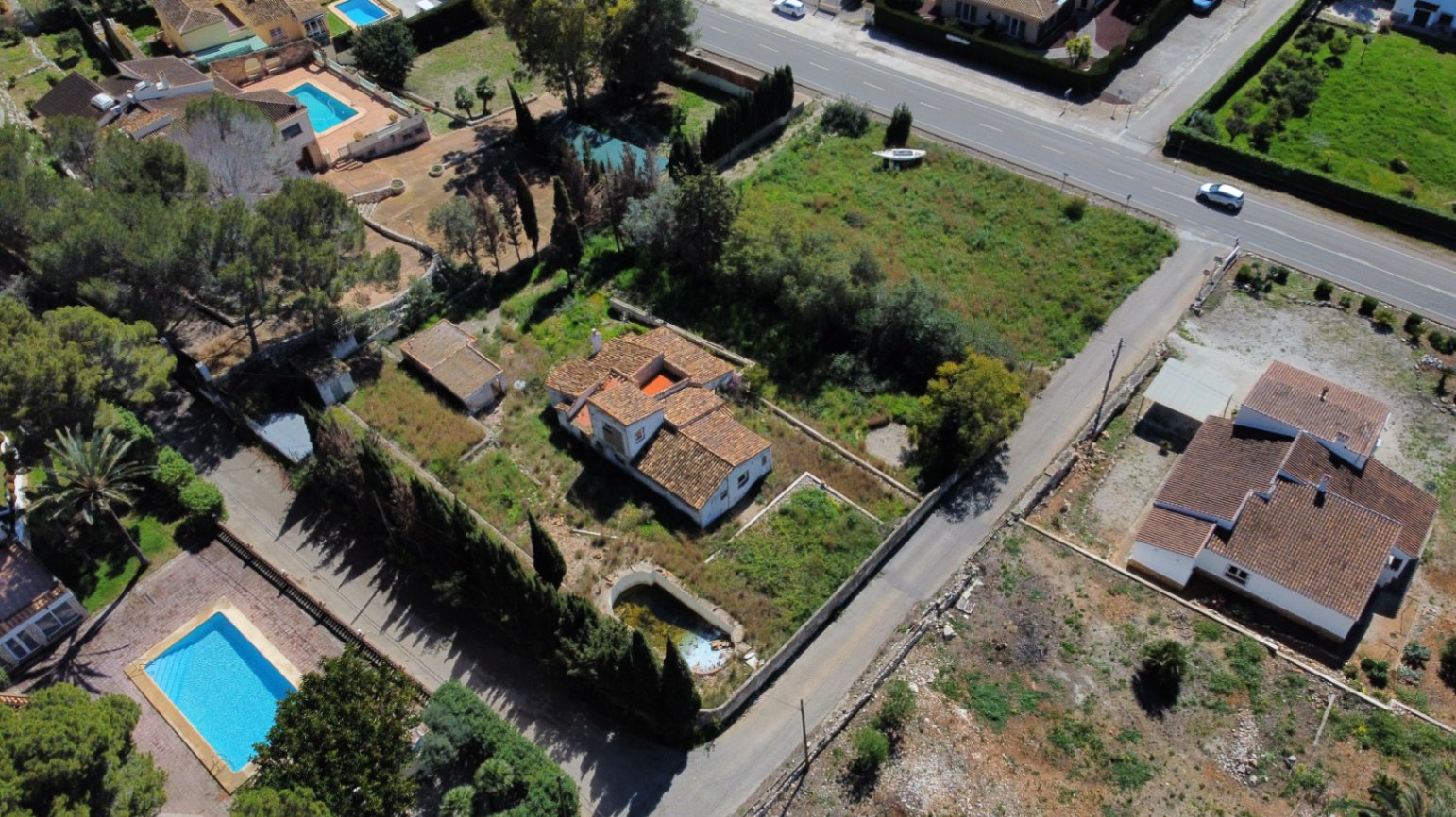 Luchtfoto van het perceel van 2.895 m2 met de traditionele villa, een te renoveren zwembad en een ruim terrein met mediterrane beplanting en directe wegtoegang.