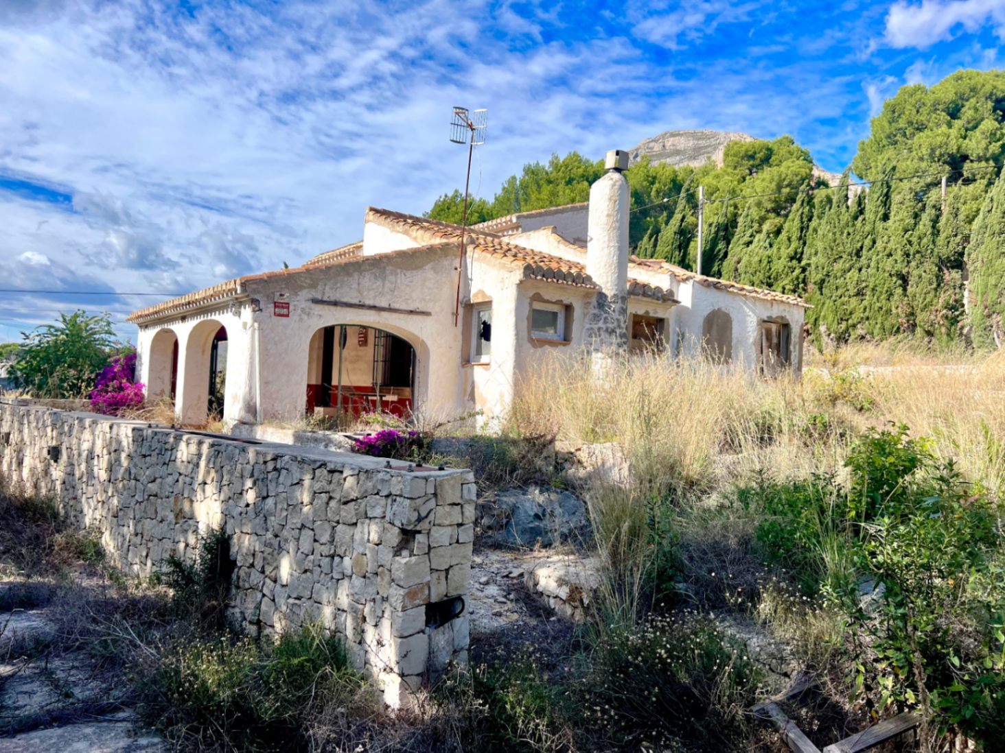 Traditionele villa met een naya met bogen en stenen schoorsteen tegen de achtergrond van de Montgó. Het perceel heeft een natuurstenen muur en behoeft volledige renovatie.