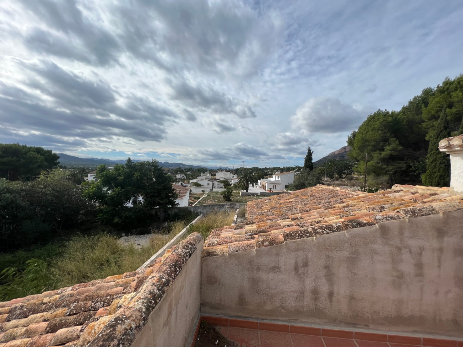 Weids uitzicht vanaf het boventerras over de Montgó-vallei, met traditionele dakpannen en de groene mediterrane omgeving van Jávea.