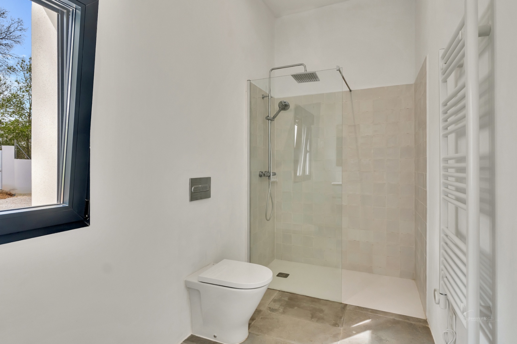 Moderne badkamer met inloopdouche, glazen wand en beige wandtegels. Voorzien van een hangend toilet, witte handdoekradiator en een natuurstenen vloer.