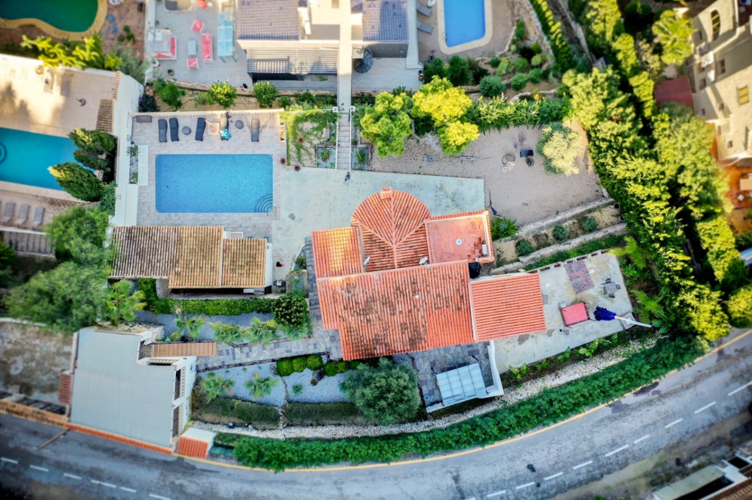 Luchtfoto van de villa met de indeling van het perceel, het rechthoekige zwembad met stenen terras en de traditionele pannendaken.