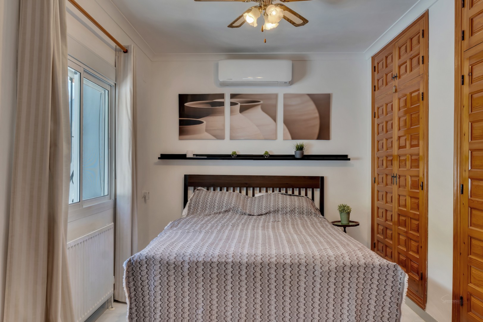 Lichte slaapkamer met ingebouwde kasten van bewerkt hout, airconditioning, een plafondventilator en dubbele beglazing met radiator.